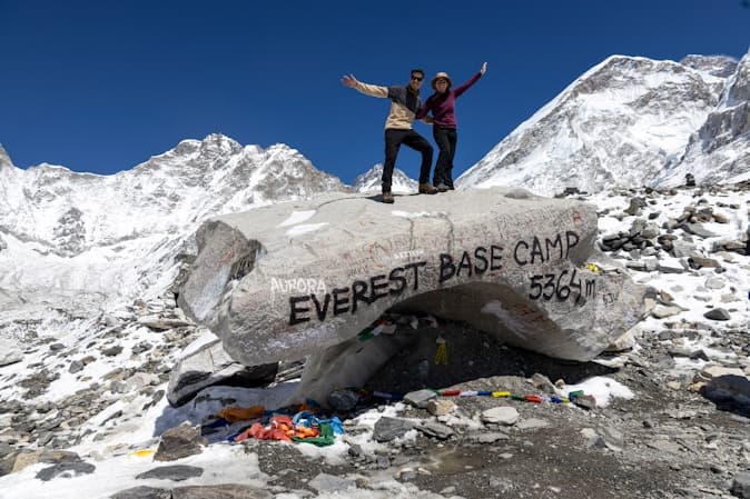 Everest Base Camp Trek showing hikers on a large boulder facing Everest