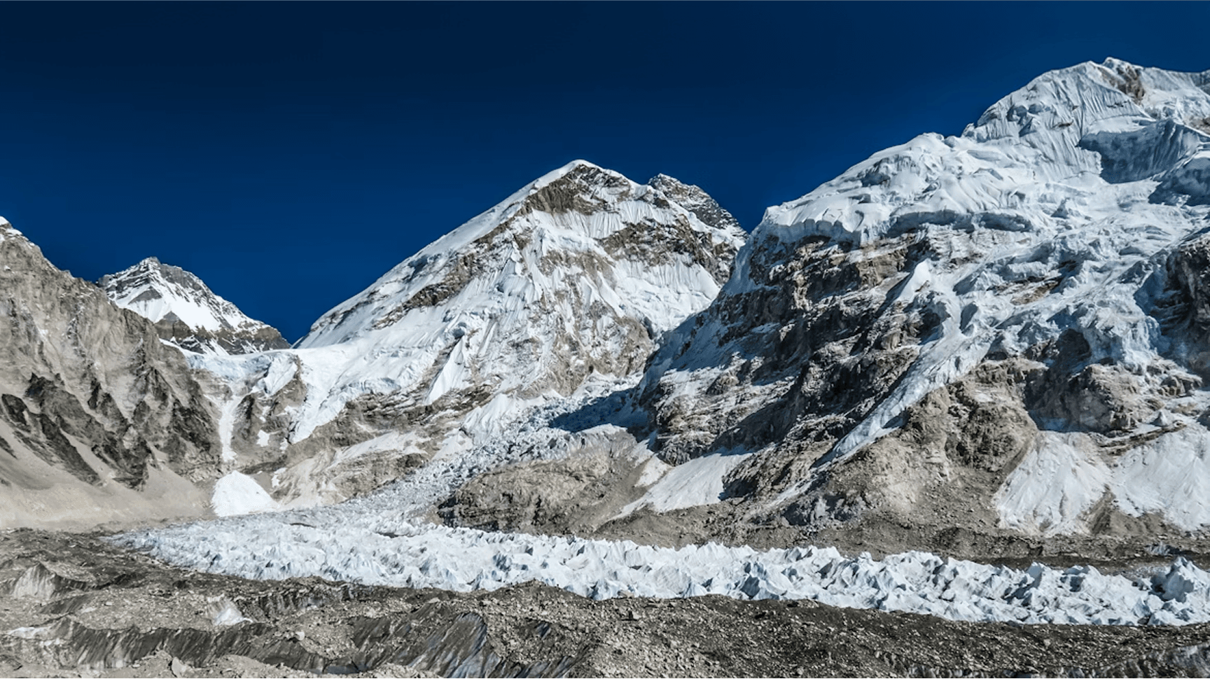 Snow-covered Khumbu mountains and glacial terrain under a blue sky