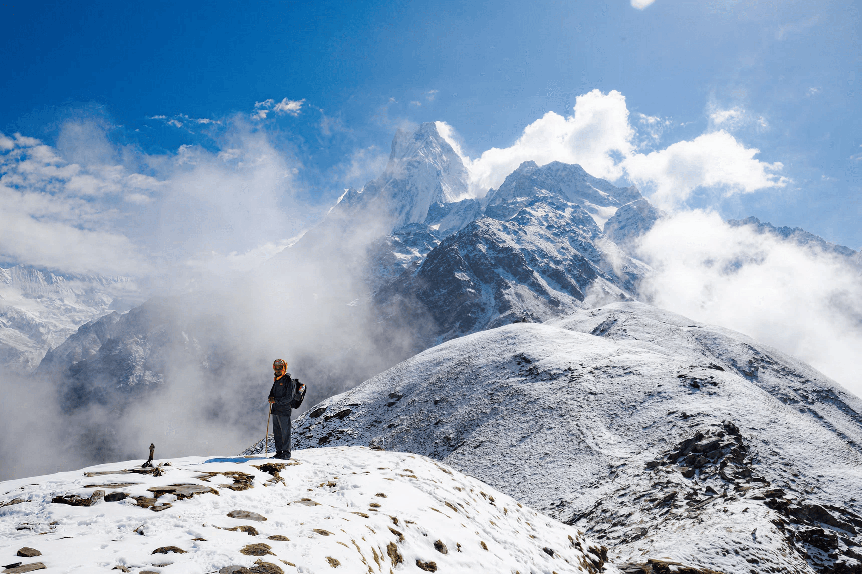 Climber standing before Everest region mountains and clouds